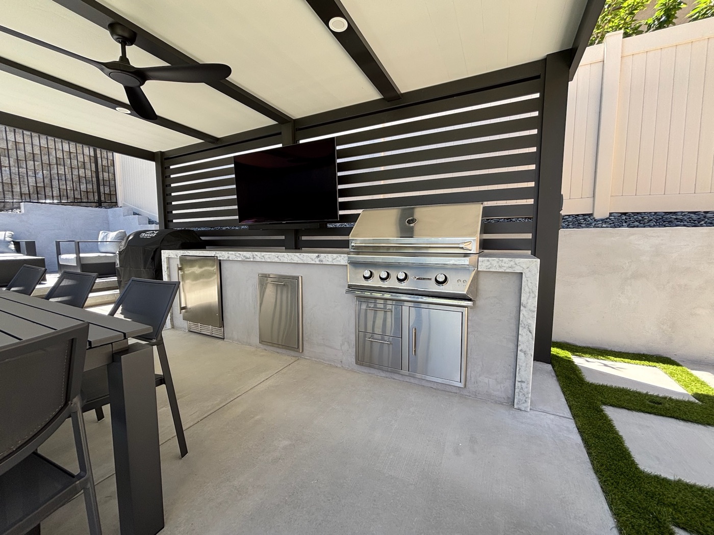 Louvered outdoor kitchen with grill and TV in Youngsville by Abshire Brothers Lawn & Landscape